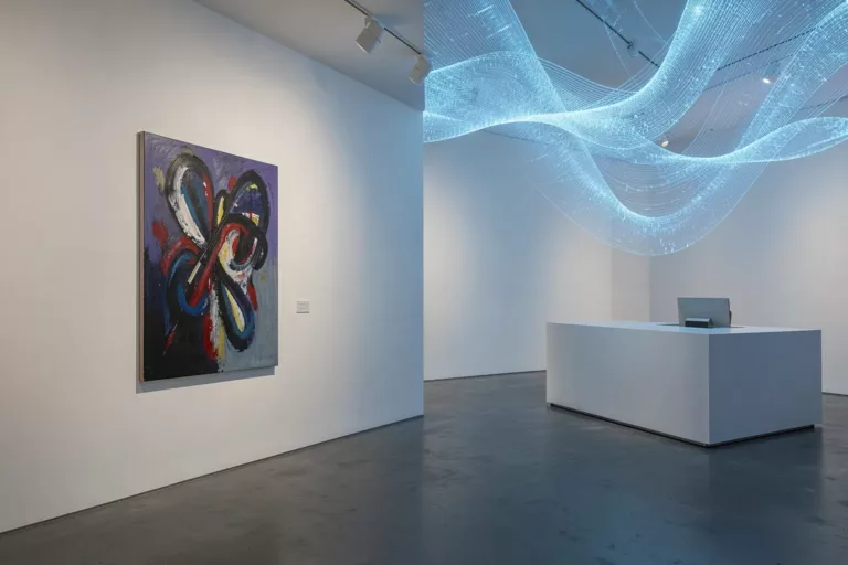 Modern gallery interior split between a human abstract painting and glowing blue AI data flows